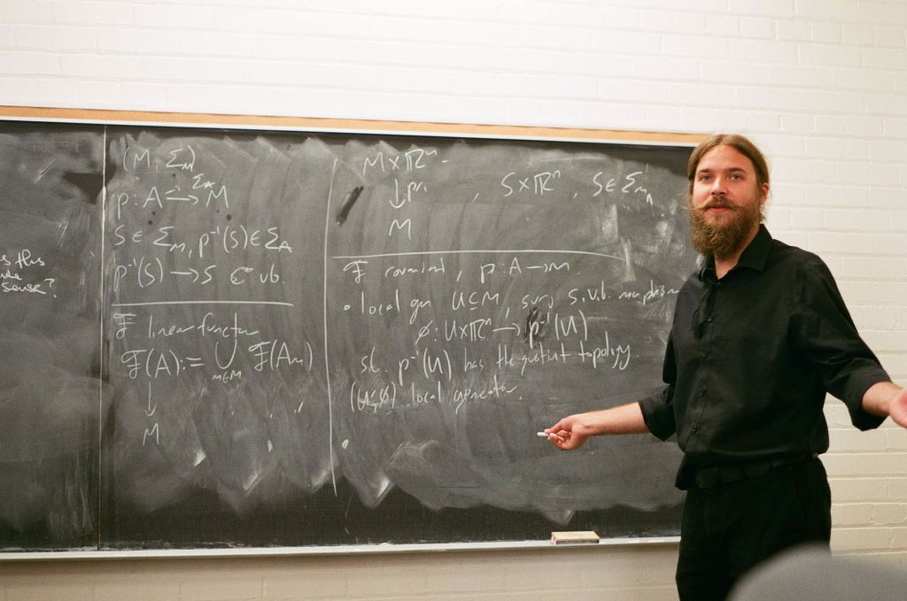 Ethan Ross standing at chalkboard displaying math